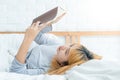 Young Asian woman enjoying lying on the bed reading book pleasure in casual clothing at home. Relaxing concept Royalty Free Stock Photo