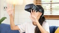 Young asian woman exciting in VR headset looking up and trying to touch objects in virtual reality at home living room, Teenager Royalty Free Stock Photo