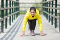 Young asian woman exercising outdoor in yellow neon jacket, getting ready for sprinting Royalty Free Stock Photo