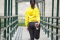 Young asian woman exercising outdoor in yellow neon jacket, stretching Royalty Free Stock Photo