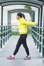 Young asian woman exercising outdoor in yellow neon jacket, stretching Royalty Free Stock Photo