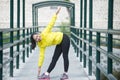 Young asian woman exercising outdoor in yellow neon jacket, stretching Royalty Free Stock Photo