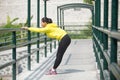 Young asian woman exercising outdoor in yellow neon jacket, stretching Royalty Free Stock Photo