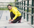 Young asian woman exercising outdoor in yellow neon jacket, tying her shoelace Royalty Free Stock Photo