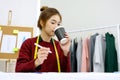 Young asian woman fashion designer working and drinking coffee at office desk in studio background, small business owner, fashion