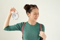 Young asian woman feeling confused and uncertain, doubting with puzzled look holding a clock