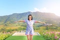 Young Asian woman feeling free with arms wide open at beautiful trees and mountains on blue sky with white puffy cloud Royalty Free Stock Photo