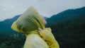 Young Asian woman feeling happy playing rain while wearing raincoat walking near forest. Lifestyle women enjoy and relax in rainy