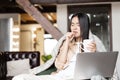 Young asian woman feeling sick, coughing and drinking hot tea. Girl catching cold, staying at home with laptop computer Royalty Free Stock Photo