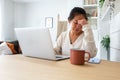 Young Asian woman feeling tired and having headache after working long hours at home office. Royalty Free Stock Photo