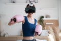 Young Asian woman fighter boxer fit girl in VR glasses wearing boxing gloves playing a boxing game at home. Royalty Free Stock Photo