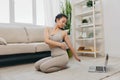 Young Asian woman in front of her laptop doing sports and yoga repeating exercises on video at home, home workout Royalty Free Stock Photo