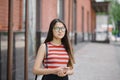 Young Asian woman with glasses hold smartphone in hands.