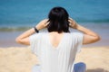 Young asian women in a gray dress wearing headphones, listening to music at the beach. Blue sky and crystal sea of tropical beach Royalty Free Stock Photo