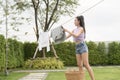 Young asian woman hanging laundry on washing line for drying against blue sky outdoor Royalty Free Stock Photo