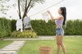 Young asian woman hanging laundry on washing line for drying against blue sky outdoor Royalty Free Stock Photo