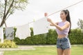 Young asian woman hanging laundry on washing line for drying against blue sky outdoor Royalty Free Stock Photo