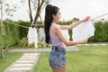 Young asian woman hanging laundry on washing line for drying against blue sky outdoor