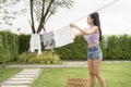 Young asian woman hanging laundry on washing line for drying against blue sky outdoor Royalty Free Stock Photo