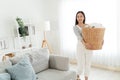 .Young Asian woman happy taking messy dirty clothes into the basket in living room at home. Beautiful cleaning service Royalty Free Stock Photo