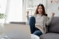 Young Asian woman are having fun and excitement sitting on the sofa. She was reading the news on a laptop at home Royalty Free Stock Photo