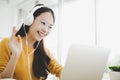 Young asian woman in headphone having conversation chatting while using laptop at house. Work at home Royalty Free Stock Photo