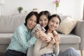 Young Asian woman with her cute daughter and mature mother hugging and smiling at camera indoors Royalty Free Stock Photo