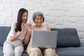 Young asian woman and her grandmother waving hand via remote communication through laptop computer in the living room. Happy Royalty Free Stock Photo