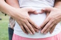 Young asian woman and her husband together caressing her pregnant belly holding their hands in a heart shape on her baby bump. Pr Royalty Free Stock Photo