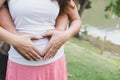 Young asian woman and her husband together caressing her pregnant belly holding their hands in a heart shape on her baby bump. Pr Royalty Free Stock Photo