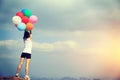 Young asian woman hold up colored balloons on mountain peak Royalty Free Stock Photo