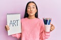 Young asian woman holding art notebook and colored pencils looking at the camera blowing a kiss being lovely and sexy Royalty Free Stock Photo