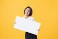 Young Asian woman holding blank paper with smiling face and looking on the orange background. for advertising signs. Royalty Free Stock Photo