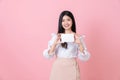 Young Asian woman holding blank paper with smiling face and looking on the pink background. for advertising signs. Royalty Free Stock Photo