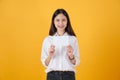 Young Asian woman holding blank paper with smiling face and looking on the yellow background. for advertising signs. Royalty Free Stock Photo