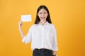 Young Asian woman holding blank paper with smiling face and looking on the yellow background. for advertising signs. Royalty Free Stock Photo