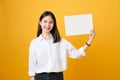 Young Asian woman holding blank paper with smiling face and looking on the yellow background. Royalty Free Stock Photo