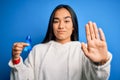 Young asian woman holding blue cancer ribbon symbol standing over isolated background with open hand doing stop sign with serious Royalty Free Stock Photo