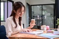 Young woman holding coffee cup and checking financial reports at office desk. Royalty Free Stock Photo