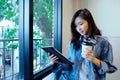 Young asian woman holding a coffee cup and digital tablet sitting in room, lifestyle, working from home, adult online education