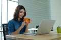 Young asian woman holding a coffee cup with smiling face, positive emotion at working desk background, casual office life, working