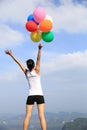 Young asian woman holding colored balloons on the mountain peak Royalty Free Stock Photo