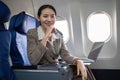 Young Asian woman holding credit card shopping online using website on laptop Sitting near window in first class on Royalty Free Stock Photo