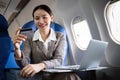 Young Asian woman holding credit card shopping online using website on laptop Sitting near window in first class on Royalty Free Stock Photo