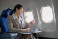 Young Asian woman holding credit card shopping online using website on laptop Sitting near window in first class on Royalty Free Stock Photo