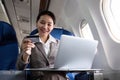 Young Asian woman holding credit card shopping online using website on laptop Sitting near window in first class on Royalty Free Stock Photo