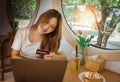 Young Asian woman holding credit card and using laptop computer. Beautiful happy young girl in cafe. Online shopping, E-commerce, Royalty Free Stock Photo