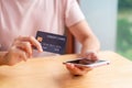 Young Asian woman holding a credit card and using smart phone for make an online shopping payment Royalty Free Stock Photo