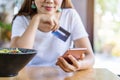 Young asian woman holding a credit card and using smart phone for make an online shopping payment Royalty Free Stock Photo