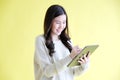 Young asian woman holding digital tablet , smiling while standing over isolated yellow background Royalty Free Stock Photo